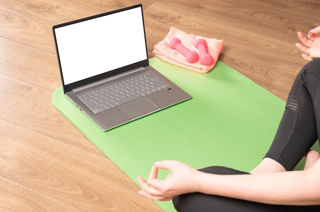 Hinten Rücken über die Schulter Ansicht bei fit sportlich gesunde ruhige Frau sitzen auf Matte in Lotus Pose beobachten Online-Yoga-Klasse meditieren machen Atemübungen
