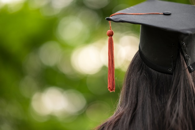 Hinter dem Foto des Universitätsabsolventen trägt ein Kleid und eine schwarze Mütze mit brauner Quaste