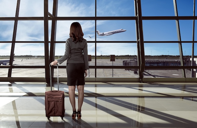 Hintere Ansicht der asiatischen Frau tragen Koffer im Flughafen