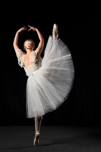 Hintere Ansicht der Ballerina im Ballettröckchenkleid mit dem Bein oben
