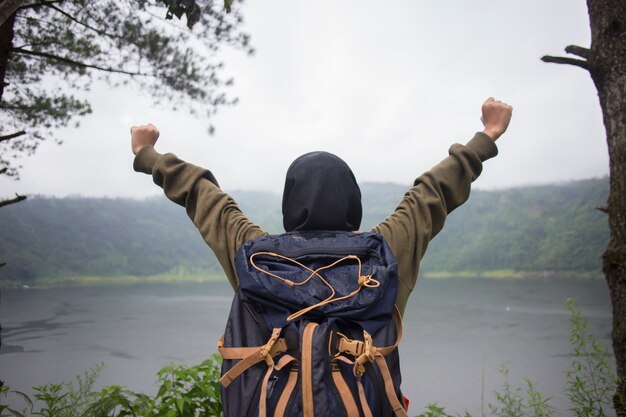 Hintere Ansicht der jungen muslimischen asiatischen Frau mit den Händen oben, die auf Klippe über See stehen. Reisekonzept, Konzepte des Gewinners, Freiheit,