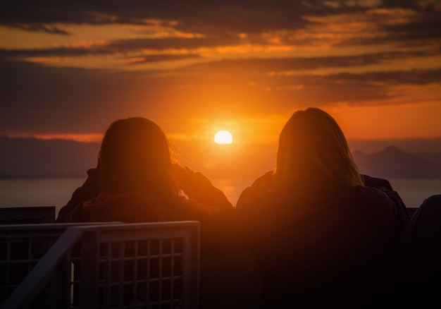 Hintere Ansicht der Reisendpaarfrau, die Meer Sonnenuntergang in Shizuoka, Japan betrachtet.