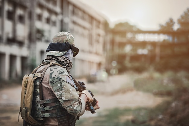 Hintere Ansicht des alleinsoldaten mit Maschinenpistole im zentralen Kriegsgebäudehintergrund