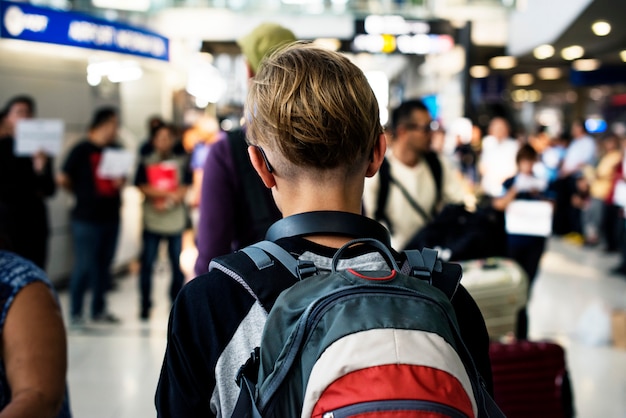 Hintere Ansicht des jungen kaukasischen Jungen, der in gedrängt am Flughafen geht