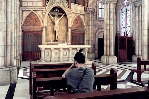 Hintere Ansicht des jungen zufälligen Mannes, der in einer Kirche betet.