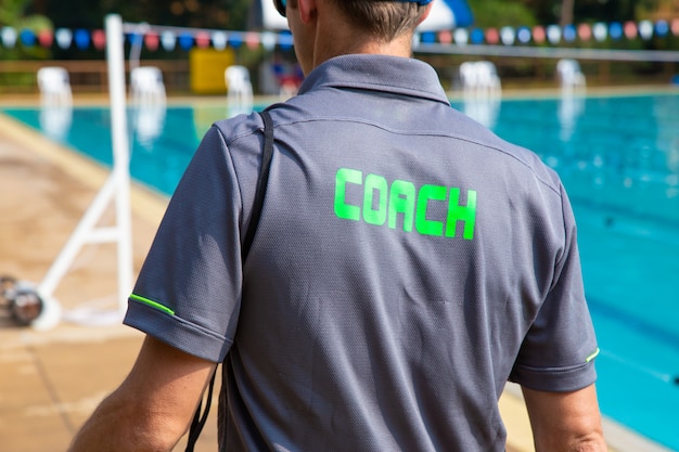 Hintere Ansicht des Schwimmensporttrainers, der durch Swimmingpool geht