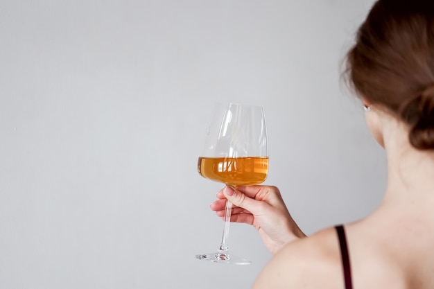 Hintere Ansicht junge Frau, die ein Glas Weißwein hält und schmeckt