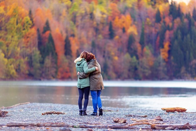 Hintere Ansicht von Mädchen, die Herbstberge und See betrachten, die schönen Sonnenuntergangansicht bewundern