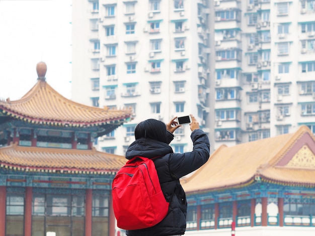 Hinterer Ansichtfrauentourist, der Foto vom Smartphone über chinesischem Gebäude macht