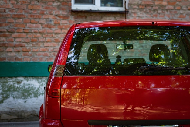 Hinteres Fenster des roten Autos, das am sonnigen Sommertag auf der Straße geparkt wird, Rückansicht Mock-up für Aufkleber oder Abziehbilder