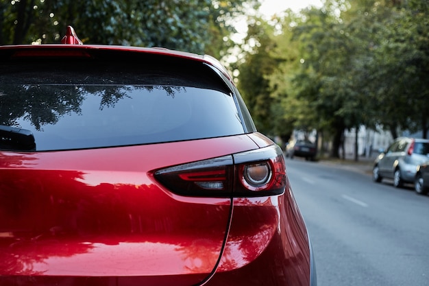 Hinteres Fenster des roten Autos geparkt auf der Straße im sonnigen Sommertag, Rückansicht. Modell für Aufkleber oder Abziehbilder