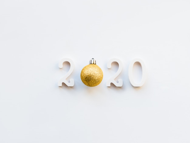 Hintergrund 2020 des neuen Jahres mit goldener Kugel. Nr. 2020 auf weißem Kopienraum mit dekorativer Kugel für Weihnachtsbaum.