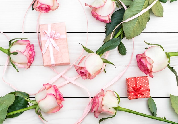 Hintergrund aus Geschenkboxen und Rosen auf dem weißen Holztisch