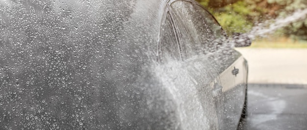 Hintergrund der Autowaschanlage, Wassertropfen auf der linken Seite (Platz für Text) Farbverlauf zum Foto von Wasser und Shampoo-Spray, silberne Autoseite.