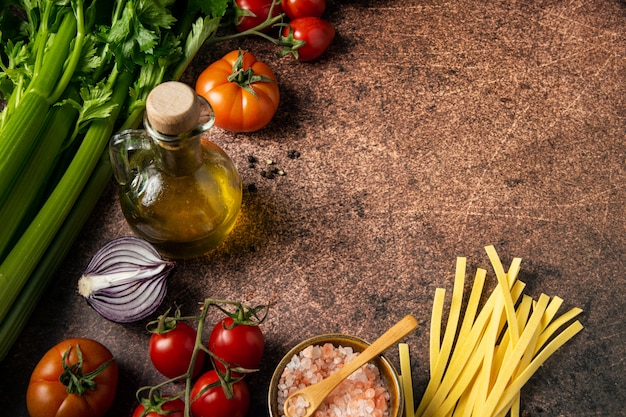 Hintergrund der italienischen Küche Zutaten, Nudeln, Gemüse, Wein, Olivenöl auf dunklem rustikalem Hintergrund