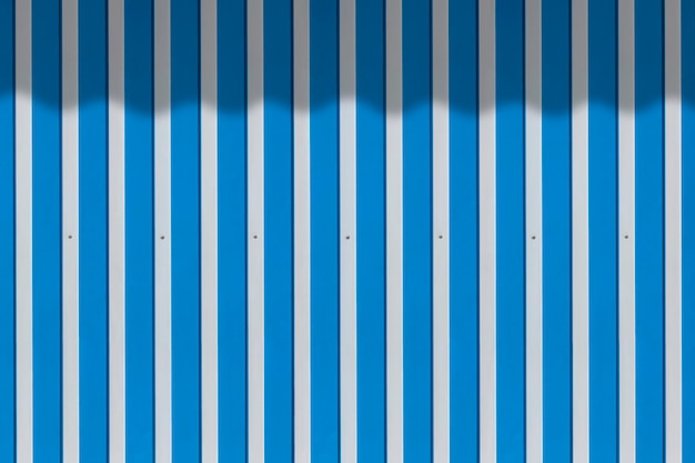 Hintergrund der weiß und blau gestreiften Aluminiumstahlwand mit Schatten der Segeltuchmarkise auf der Oberfläche
