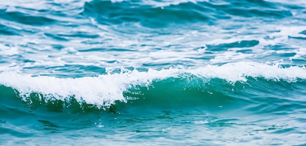 Hintergrund der Wellen des Ozeans, die auf den Strand stürzen, die Wellen des Wassers, die in Sprühen wellen, das Wasser spritzt, das klare Wasser.