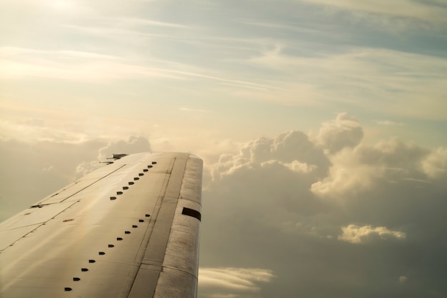 Hintergrund des blauen Himmels mit weißen Wolken. Aufgedunsene Wolken am Horizont. Blick aus dem Flugzeugfenster auf den Flügel.