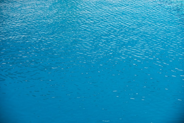 Hintergrund des blauen Wassers im Swimmingpool mit Sonnenreflexions-Wasserwelle im Pool Klarer Wasserhintergrund