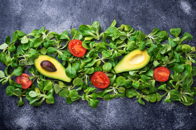 Hintergrund des grünen Lebensmittels mit Feldsalat, Tomate und Avocado