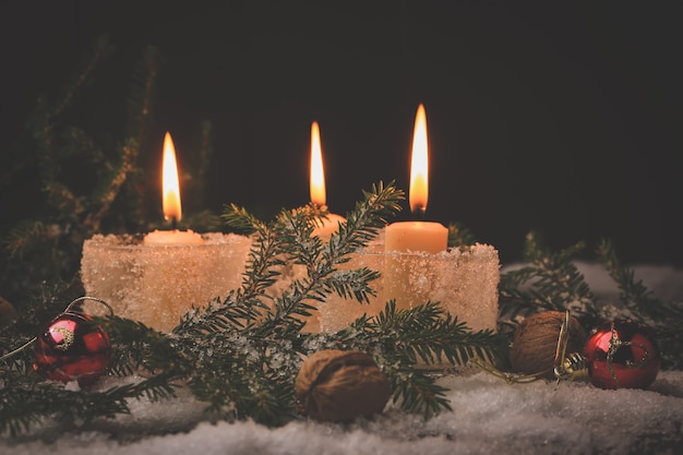 Hintergrund des neuen Jahres. Brennende Weihnachtskerzen mit Tannenbaum im Schnee