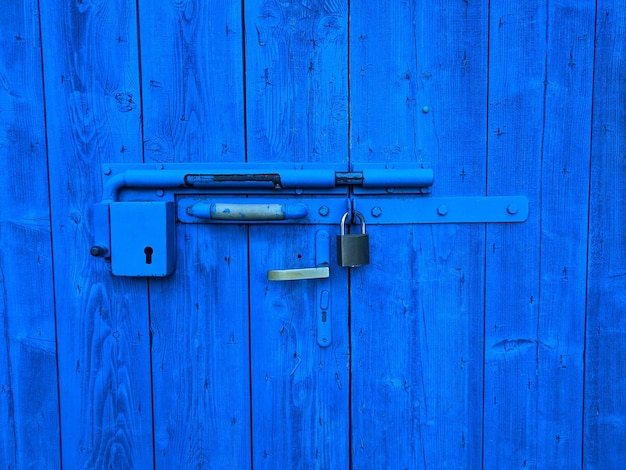 Hintergrund des Vintage-Griffs an einer alten blauen Holztür aus nächster Nähe. Rissige Farbe.