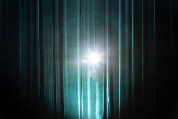 Hintergrund eines dunkelgrünen Theatervorhangs mit einem Strahl von einer Lichtquelle Bühnenhintergrund