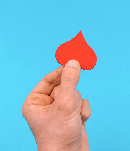 Hintergrund für die Wohltätigkeitsorganisation des Weltblutspendetages und das helfende Handkonzept Mann, der rotes Herz hält und es anderen gibt