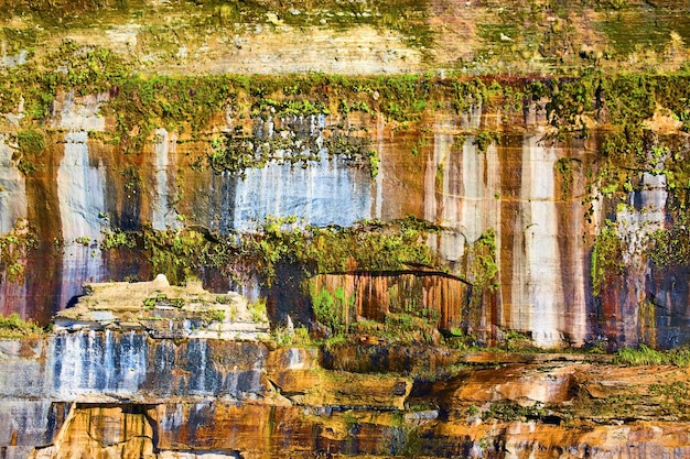 Hintergrund: grüne Moosflechten, die an den abgebildeten Felsen wachsen, mit herabtropfenden Mineralien