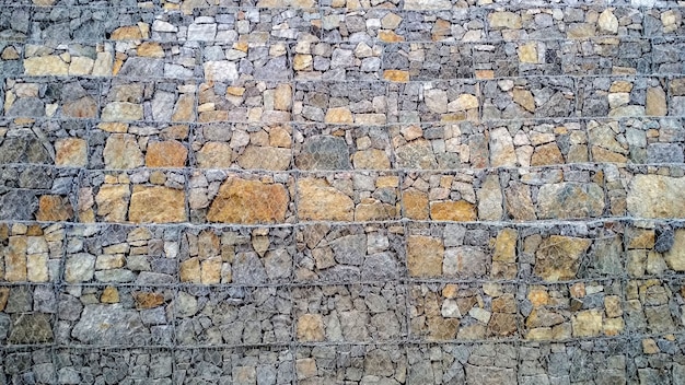 Hintergrund in Form von gestapelten Steinen und mit gewebtem Metallgitter befestigt
