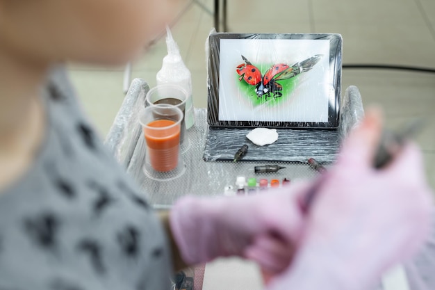 Hintergrund ist ein Tablett mit einem Bild eines Marienkäfers im Tattoo-Salon