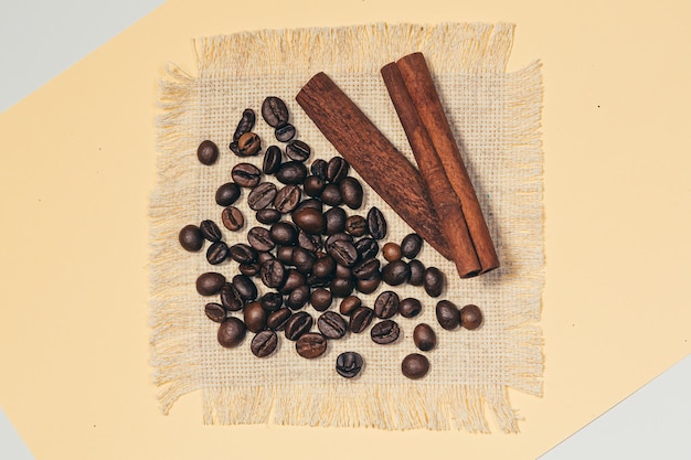 Hintergrund, Kaffee, Kaffeebohnen und Zimtstangen auf Leinentuch, auf weißem und beigem Hintergrund, isoliert