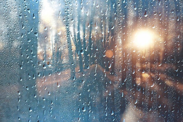 Hintergrund nasses Glas fällt Herbst im Park / Blick auf die Landschaft im Herbstpark aus einem nassen Fenster, das Konzept des Regenwetters an einem Herbsttag