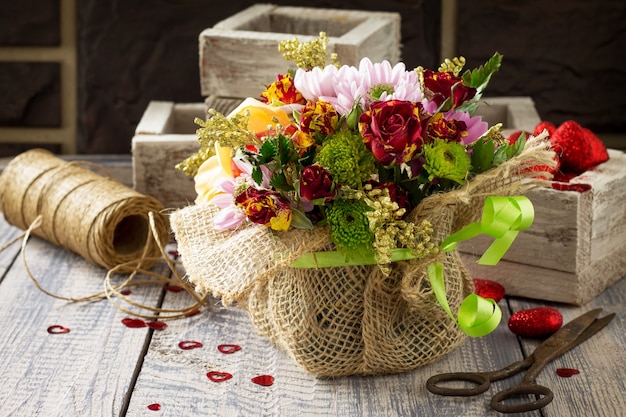 Hintergrund Valentinstag oder Hochzeit. Korbstrauß aus Rosen und Chrysanthemen.