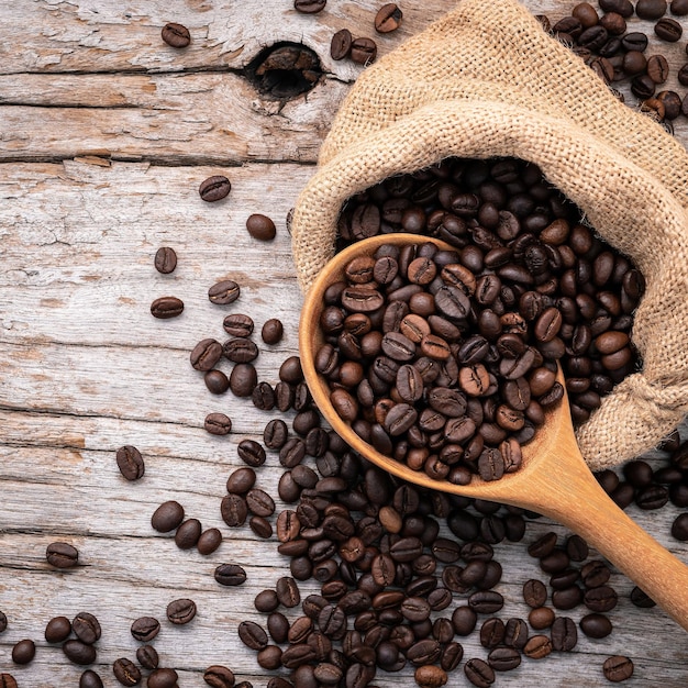 Hintergrund von dunkel gerösteten Kaffeebohnen mit Schaufeln auf Holzhintergrund mit Kopierraum