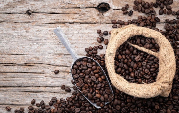 Foto hintergrund von dunkel gerösteten kaffeebohnen mit schaufeln auf holzhintergrund mit kopierraum