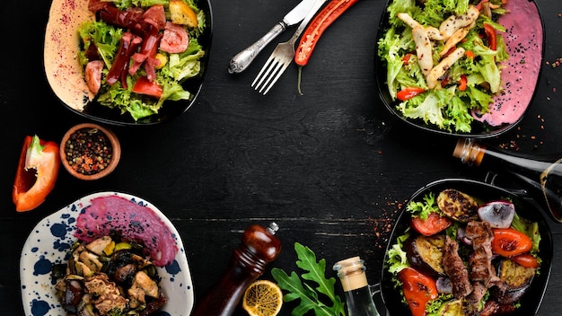 Hintergrund von Speisen und Gerichten Fleisch- und Fischgerichte und Salat Auf einem hölzernen Hintergrund Ansicht von oben Freier Platz für Ihren Text