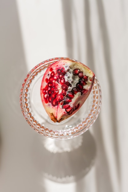 Hintergrund weiß mit Schatten aus Kristallglas und Granatapfel.