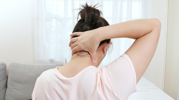 Hintergrundansicht einer asiatischen Frau, die bei einer Physiotherapie den Hals mit den Händen massiert, um P zu reduzieren