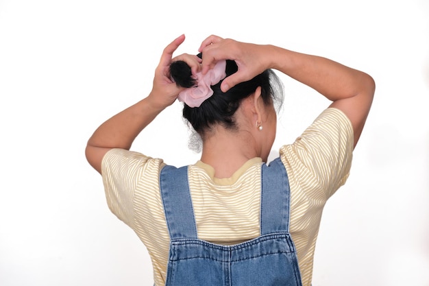 Hintergrundansicht einer asiatischen Frau, die ihr Haar aufrollt und mit einem Gummiband bindet
