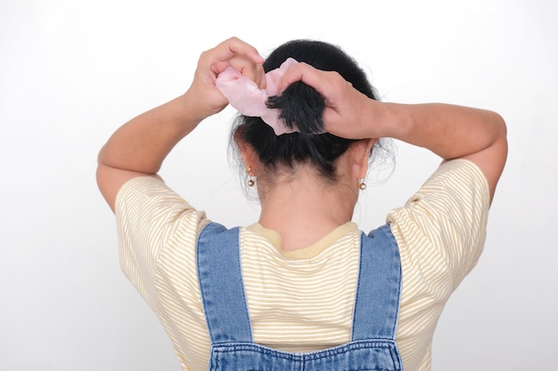 Hintergrundansicht einer asiatischen Frau, die ihr Haar aufrollt und mit einem Gummiband bindet