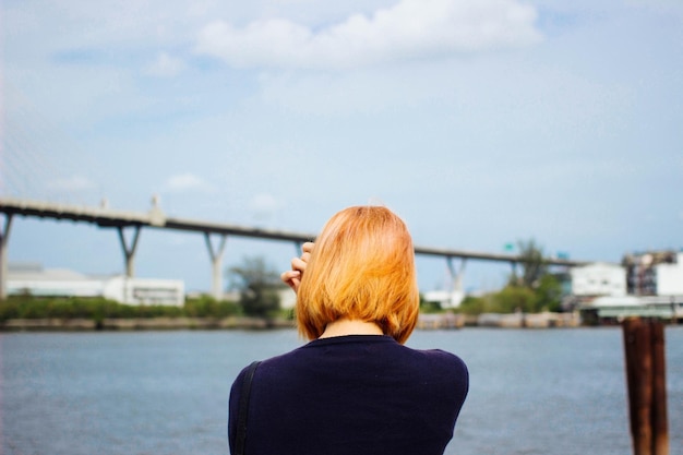 Hintergrundansicht einer Frau am Fluss gegen den Himmel