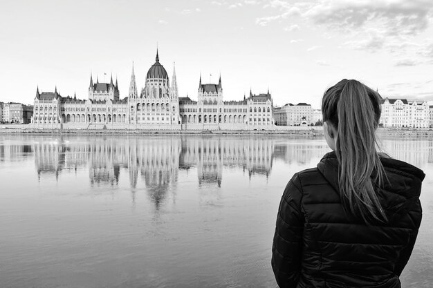 Hintergrundansicht einer Frau, die am Donau vor dem Parlament steht