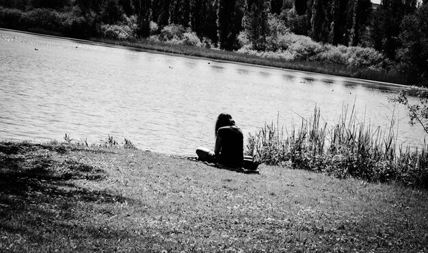 Foto hintergrundansicht einer frau, die am see sitzt