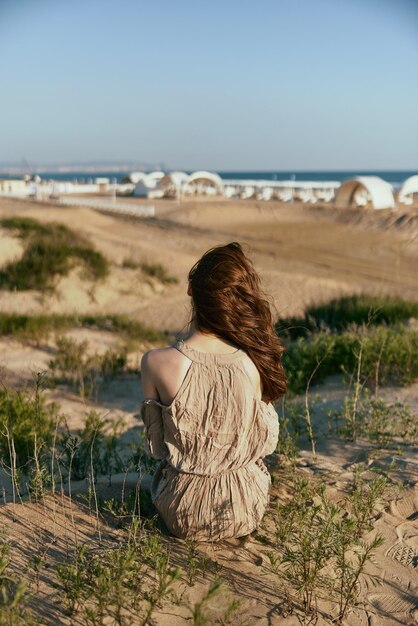 Foto hintergrundansicht einer frau, die am strand gegen den himmel sitzt