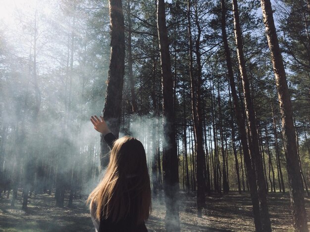 Foto hintergrundansicht einer frau, die an bäumen im wald steht