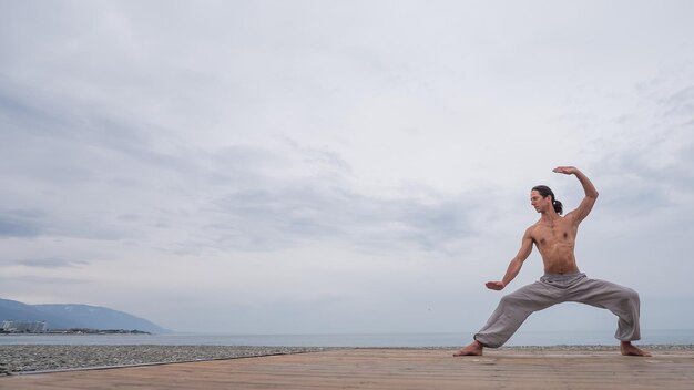 Hintergrundansicht einer Frau, die an einem Strand gegen den Himmel Yoga macht