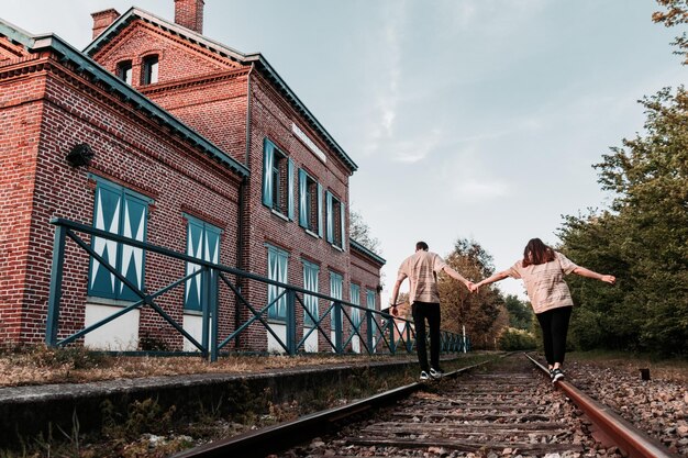 Foto hintergrundansicht einer frau, die an eisenbahnschienen vor gebäuden gegen den himmel läuft