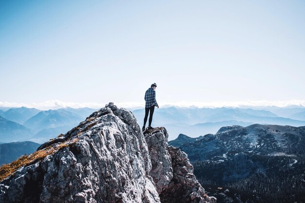 Hintergrundansicht einer Frau, die auf dem Berg gegen den Himmel steht