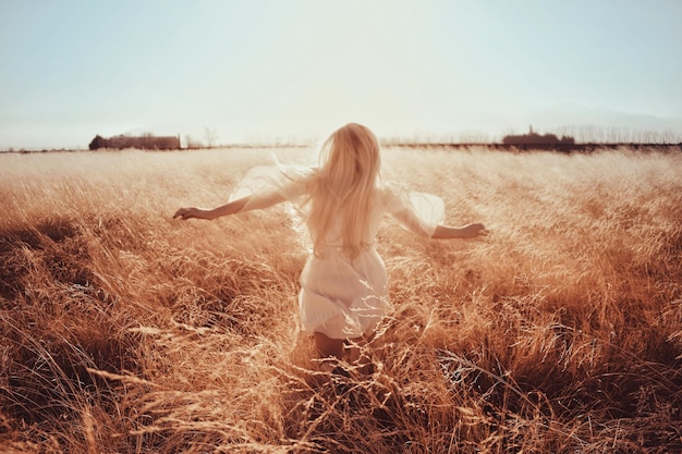 Foto hintergrundansicht einer frau, die auf dem feld gegen den himmel rennt